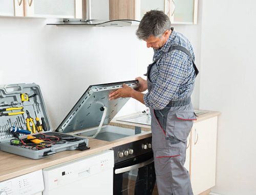 Photo Of mature repairman examining stove in kitchen